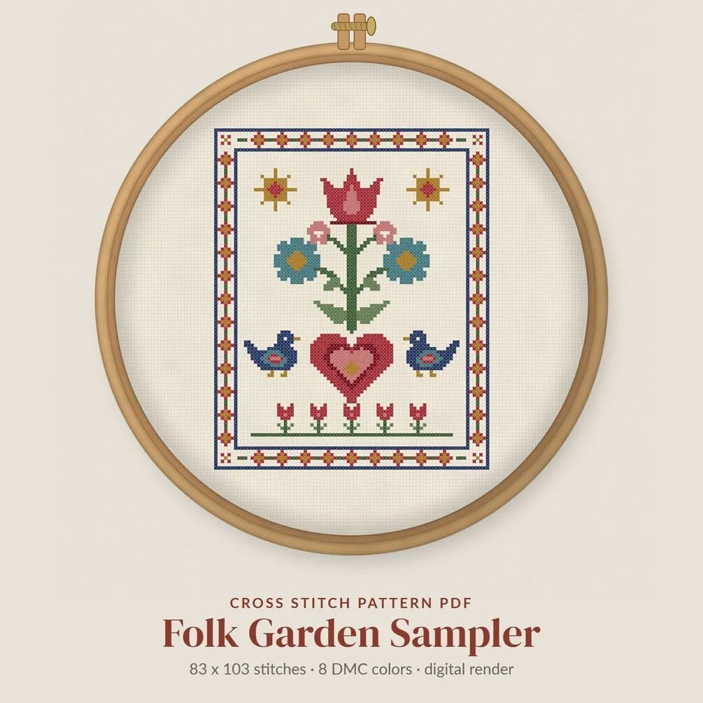 The Folk Garden Sampler in a wooden hoop: tulips, daisies, two blue birds and a heart inside a patterned border. A digital render, not a photo of a stitched piece.